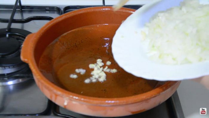 Calentar aceite de oliva en una cazuela. Añadir el ajo muy picadito y la cebolla menudita. Pochar con un poco de sal hasta que se dore (aproximadamente 15 minutos).