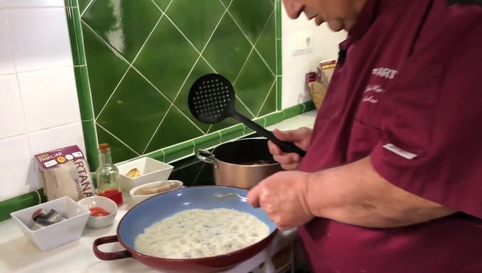 Montar la cazuela: colocar el arroz crudo, las carnes, los garbanzos, las anguilas, las patatas, el tomate y el sofrito. (312.46)