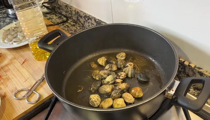 Agregar más aceite a la cazuela y freír las almejas hasta que se abran. (122.92)