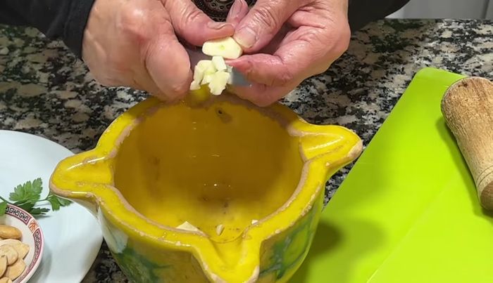 Preparar la picada: en un mortero, machacar los ajos con un poco de sal, avellanas, almendras y perejil. (193.84)
