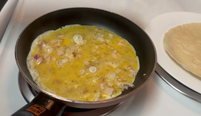 Colocar la tortilla (parte dorada hacia arriba) sobre la mezcla de huevo, aplastando ligeramente para integrar.