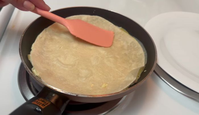 Cocinar la tortilla unos minutos, luego darle la vuelta y cocinar el otro lado.