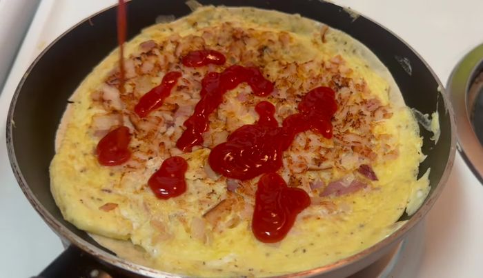 Agregar ketchup por encima, mezclar y añadir queso rallado y orégano.