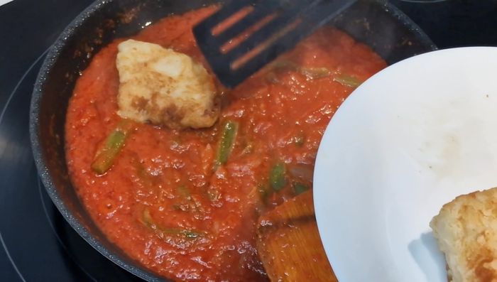 Agregar los trozos de bacalao dorado a la salsa de tomate. Dejar cocinar un minuto por cada lado para que se integren los sabores. [132.2]