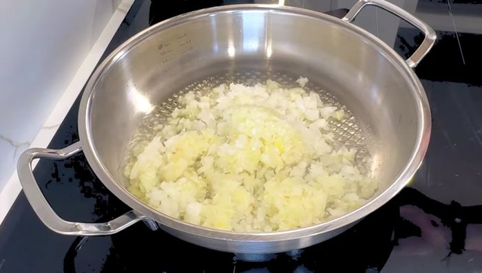 Sofreír la cebolla y el ajo en una olla con aceite de oliva virgen extra hasta que la cebolla coja color. Mientras, preparar la infusión de azafrán (agua caliente + hebras de azafrán).