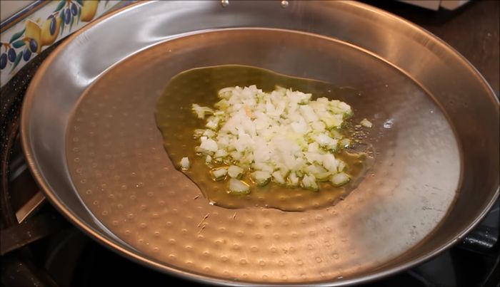 En una sartén, pochamos un poco la cebolla con un poco de sal. Añadimos el ajo picado y sofreímos durante un minuto.