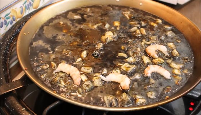 Añadimos las gambas peladas hacia el interior del arroz, procurando que no queden en la superficie.