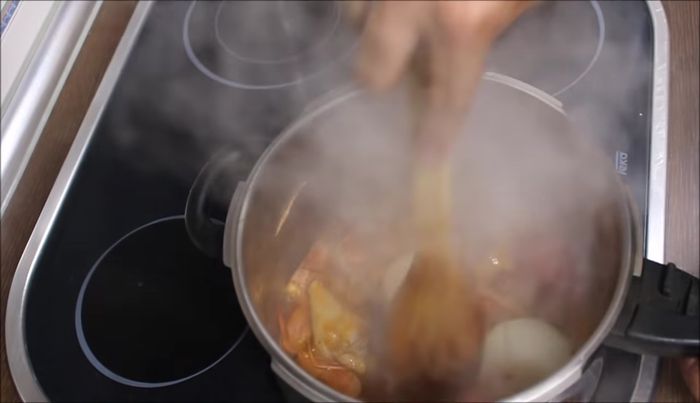 Agregamos el tomate y la cebolla (ambos partidos en dos) y cubrimos con 3 litros de agua. Dejamos cocer a fuego lento durante media hora.