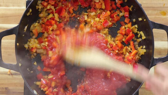 Añadir los tomates triturados y cocinar a fuego lento durante 5 minutos.