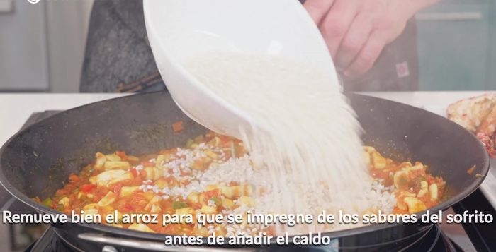 Añadir 400g de arroz bomba y remover bien para que se impregne del sofrito. Agregar un litro de caldo para paella de marisco.