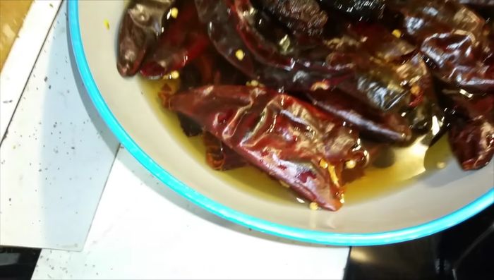 Pasar los chiles por aceite hasta que inflen y luego agregarles el vinagre blanco y agua caliente casi hirviendo. Sumergirlos bien presionándolos con un plato y un recipiente con peso encima.