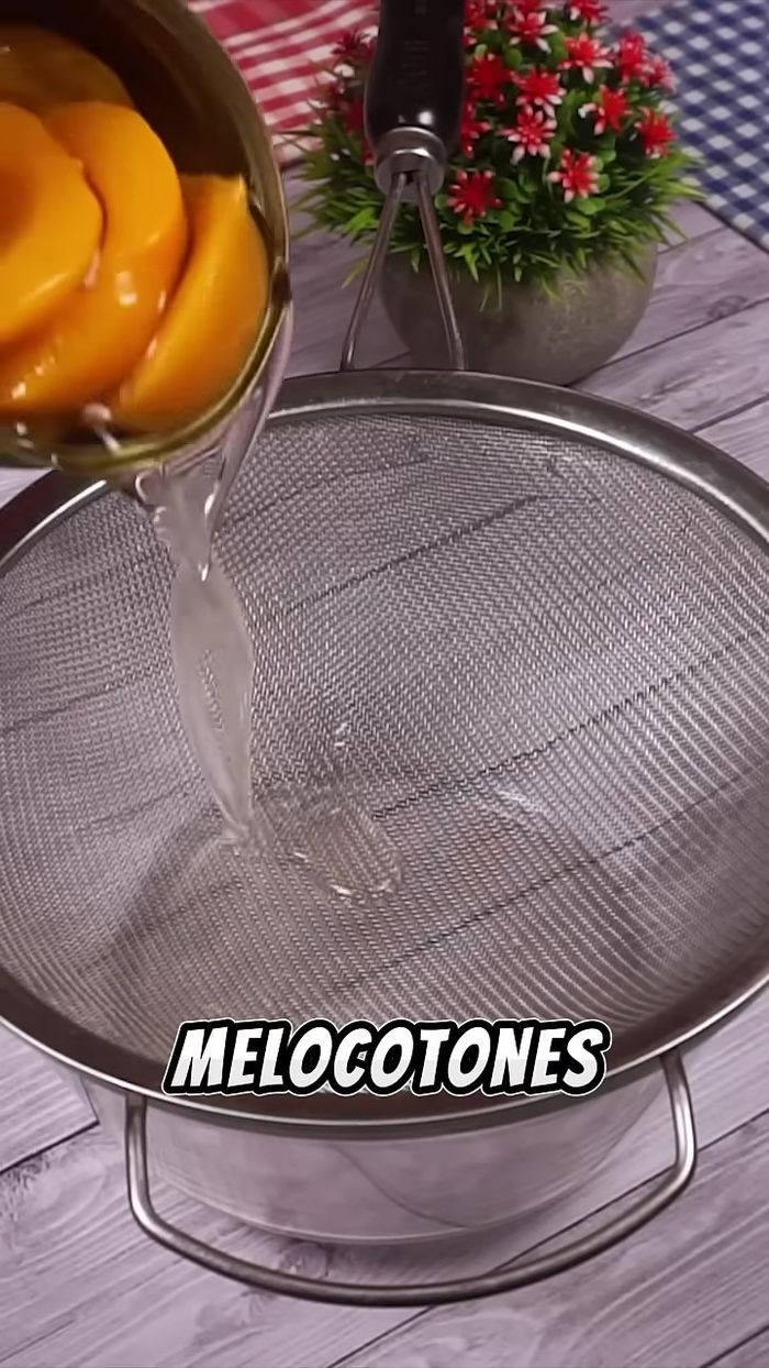 Abrir una lata de melocotones, retirar el almíbar con un colador y reservar algunos duraznos.