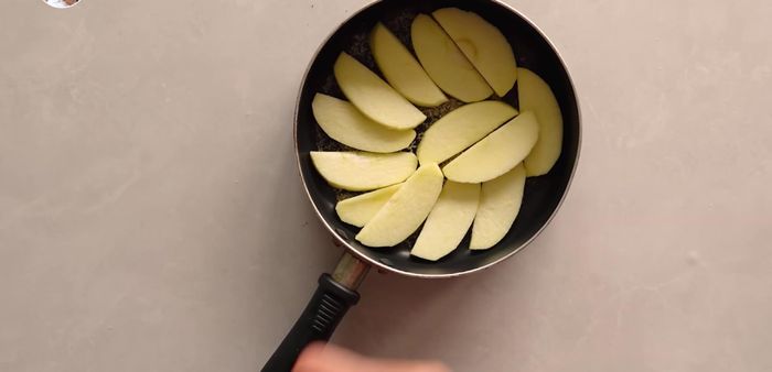 Coloca las rodajas de manzana en la sartén preparada. Agrega opcionalmente chispas de chocolate o uvas pasas.