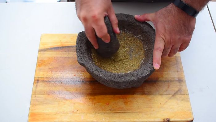 Moler en el molcajete la pimienta, el comino, el orégano y el ajo hasta formar una pasta.