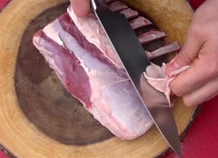 Retirar el exceso de grasa del costillar de cordero.