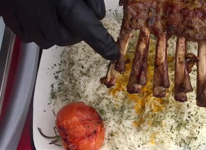 Cortar el costillar y servir sobre el arroz, decorado con tomates, perejil seco y cúrcuma.