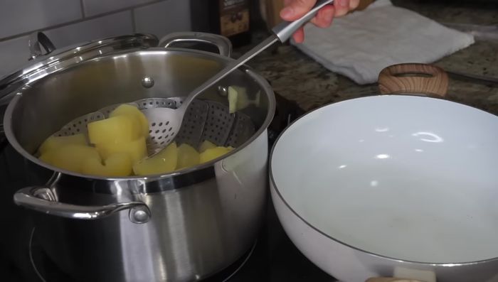 Una vez cocidas las papas, sacarlas de la olla y machacarlas con un machacador o tenedor.