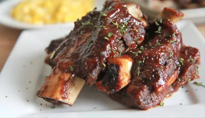 Coloque las costillas (lado carnoso hacia arriba) en la parrilla y pincélelas generosamente con la salsa. Cocine hasta que forme una costra (5 minutos).