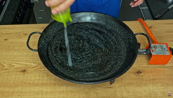 Reservamos la dorada. Añadimos un chorro de aceite de oliva a la paella y aromatizamos con un diente de ajo.