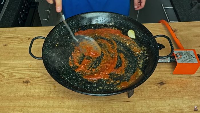 Sofreímos bien el tomate y retiramos el diente de ajo. Añadimos el arroz y lo nacaramos hasta que el grano cambie de color.