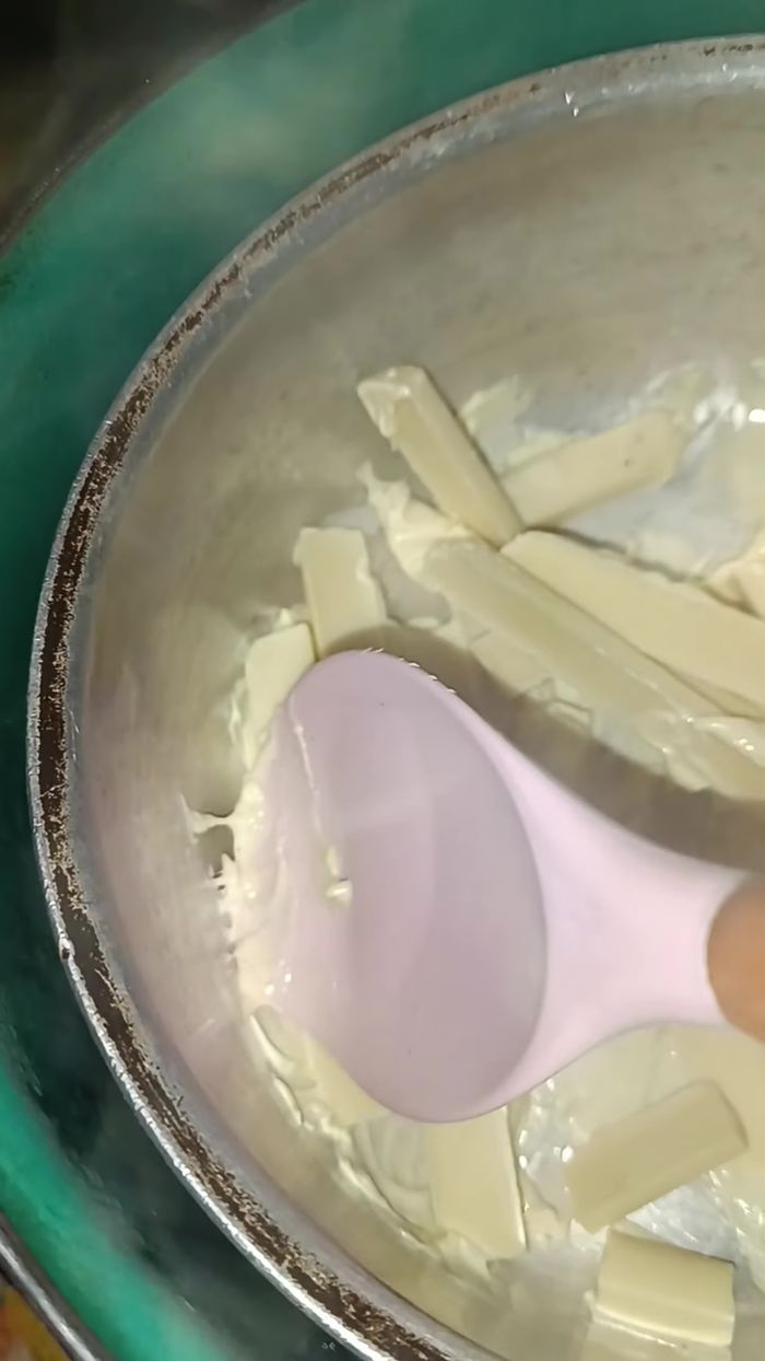 Derretir el chocolate blanco a baño maría (en una ollita pequeña sobre una olla con agua hirviendo, sin que la ollita toque el agua).