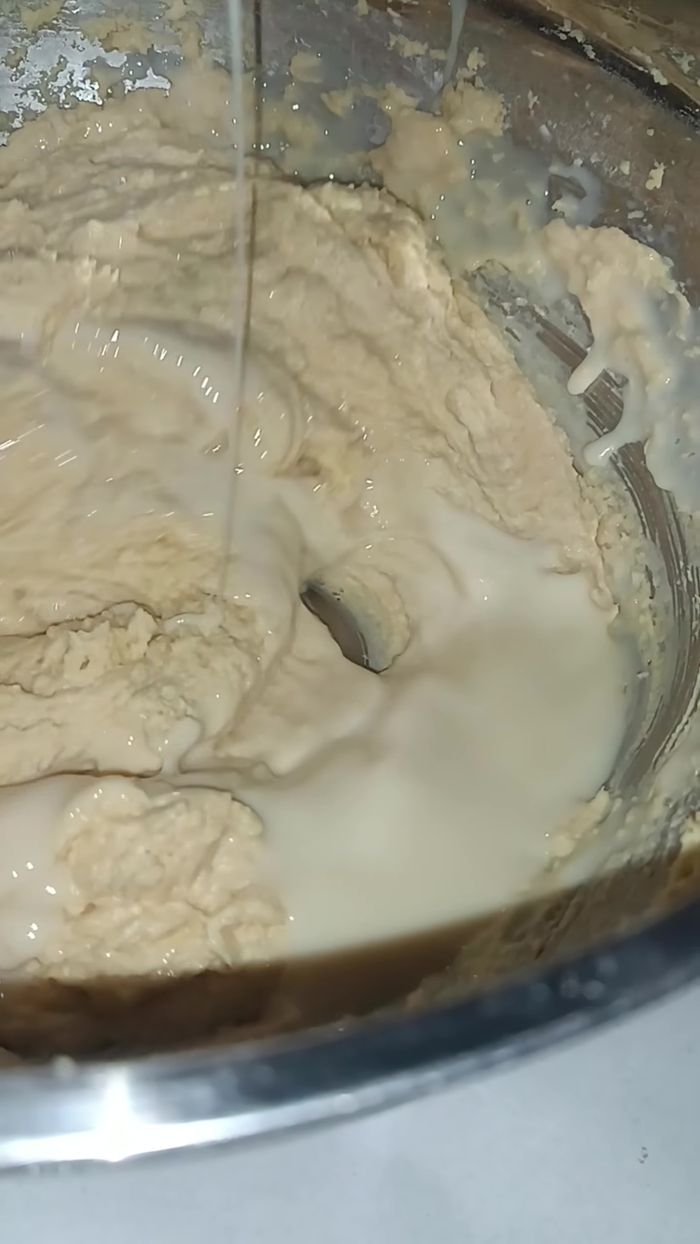 Incorporar la leche condensada, esencia de vainilla o almendra y leche a la mezcla, agregando la leche poco a poco mientras se bate.