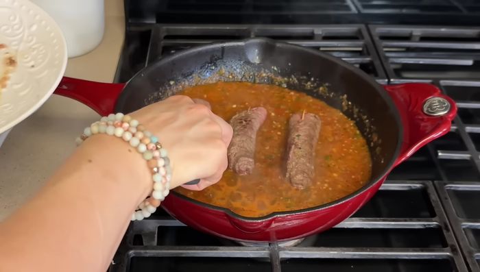Agregar los rollos de carne a la salsa. Cubrir y cocinar a fuego lento durante 15-20 minutos.