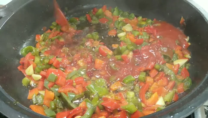 Añadir el tomate triturado (o rallado) y cocinar a fuego medio hasta que el agua se evapore.