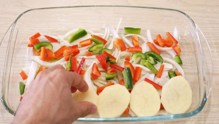 Cubrir las verduras con las patatas, añadir aceite y sal.