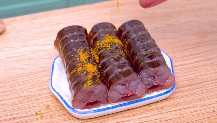 Sazonar la anguila con cúrcuma en polvo, sal, cebolla, ajo y chile. [39.52]