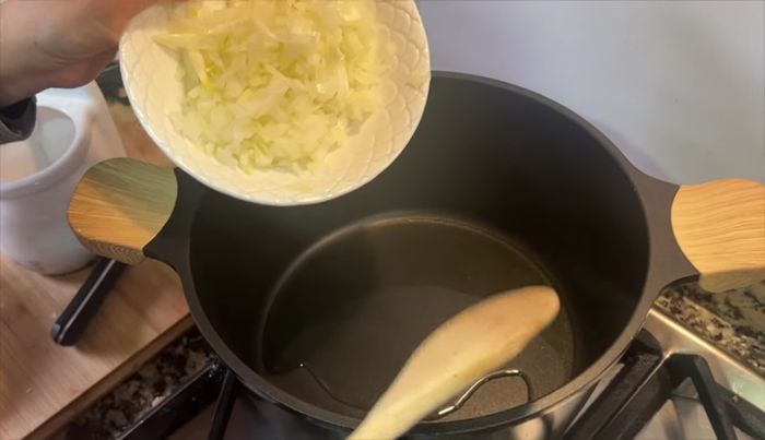 En una cazuela, echar un chorrito de aceite. Cuando esté caliente, añadir la cebolla con un poco de sal y sofreír hasta que esté dorada.