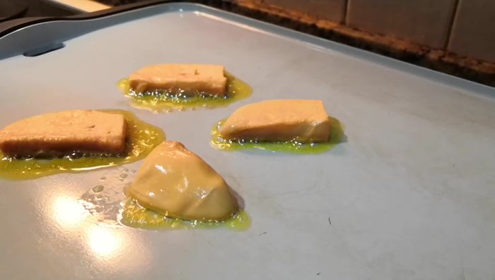 Dorar los bloques de foie a la plancha por ambos lados hasta que queden dorados por fuera y cremosos por dentro, como una película caramelizada.