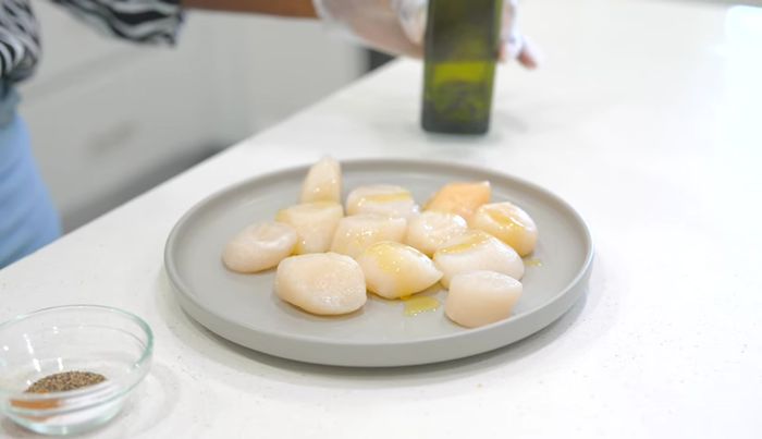 Rociar un poco de aceite sobre las vieiras.