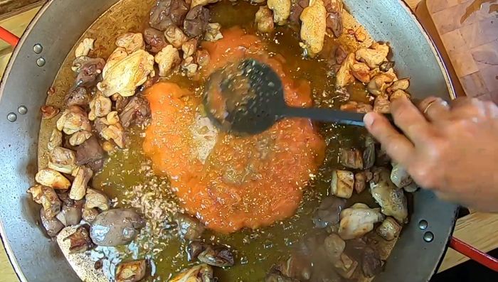 Mezclar el tomate con la grasa de la carne para desglasar la paella.