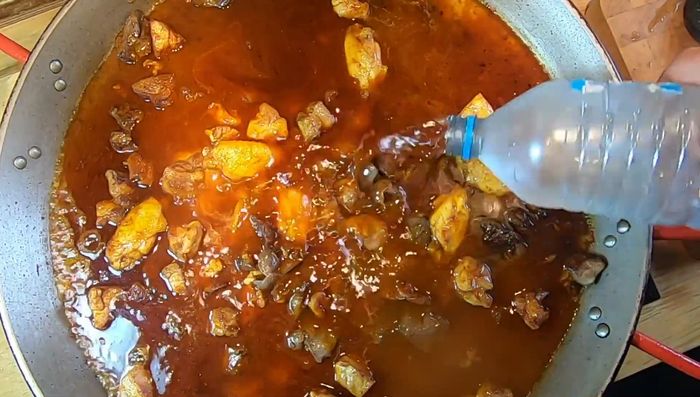 Agregar agua hasta la altura de los tornillos de la paella. Subir el fuego a medio-fuerte.