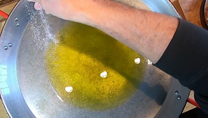 En una paella, calentar un poco de aceite (una tacita de café). Agregar sal para evitar que se queme.