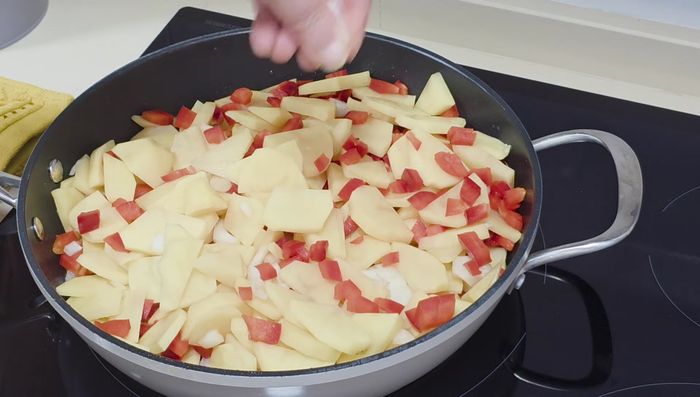 En la misma sartén, con un poco de aceite, pochar la cebolla, el pimiento y las patatas a temperatura tranquila, removiendo ocasionalmente hasta que las patatas estén tiernas y se puedan desmenuzar un poco.