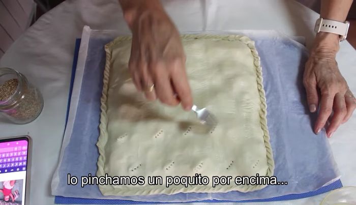 Pincha la superficie con un tenedor. Pinta con huevo batido y espolvorea con semillas de sésamo.