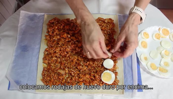 Añade rodajas finas de huevo cocido sobre la carne, cubriendo toda la superficie.