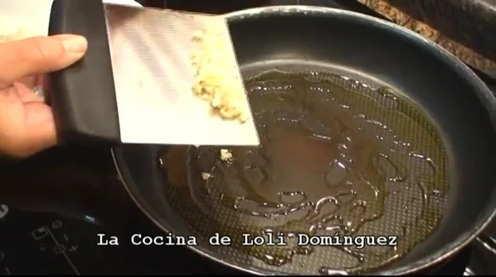 Trocear finamente el ajo. Poner unas 3 cucharadas soperas de aceite en una sartén amplia y sofreír ligeramente el ajo hasta que coja color. (40.44)