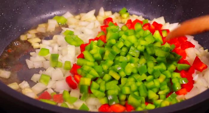En el mismo aceite, sofreír el ajo picado, la cebolla, el pimiento rojo y verde durante 10 minutos hasta que estén pochados. Agregar una pizca de sal.