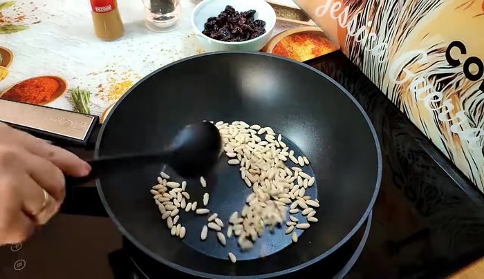 Tostar ligeramente los piñones en una sartén a fuego medio sin aceite, removiendo constantemente para evitar que se quemen.