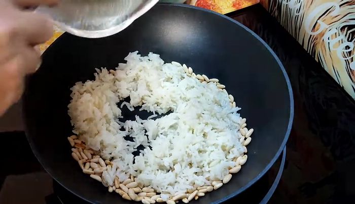 Añadir los piñones tostados al arroz, removiendo para integrarlos.