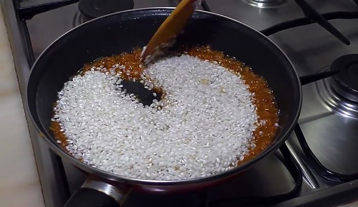 Agregar el arroz a la sartén con el tomate y sofreírlo brevemente.