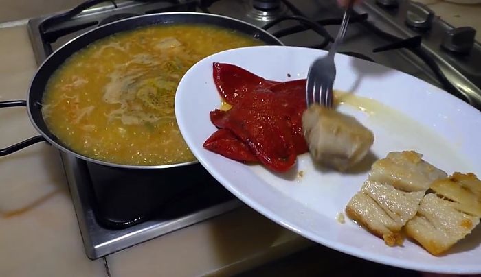 Agregar el bacalao y los pimientos a la paellera. Cocer a fuego fuerte durante 5 minutos, luego a fuego medio durante 15 minutos.