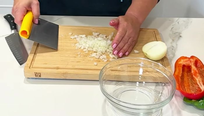 Mientras, preparar la vinagreta: picar finamente la cebolla y los pimientos. (90.28)
