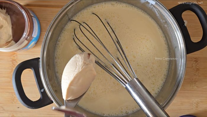 Agrega dos cucharadas grandes de crema de avellanas y chocolate blanco. Cocina a fuego medio, removiendo constantemente, hasta que espese.