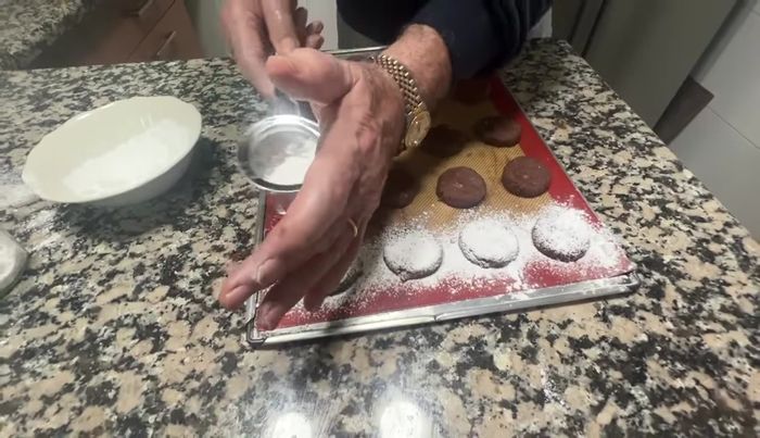 Espolvorear azúcar glass sobre las galletas y colocar una nuez entera en el centro de cada una.