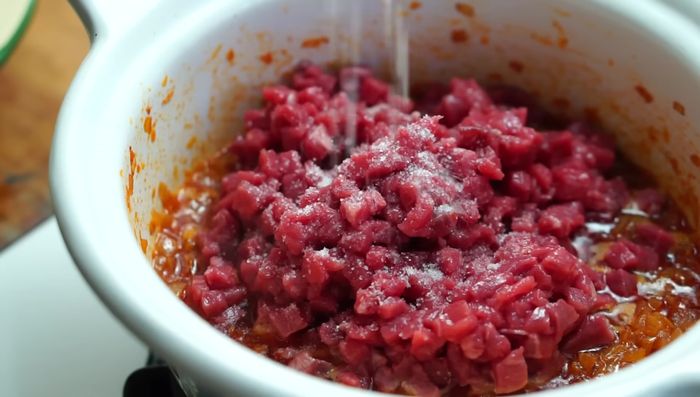 Agregar la carne al sofrito, cocinar 5 minutos hasta que pierda el color crudo. Agregar el comino molido, las papas cocidas y mezclar bien. Dejar enfriar completamente y reposar en la heladera.