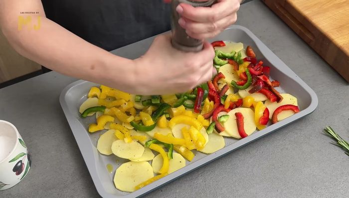 Repartimos las tiras de pimiento sobre las patatas. Salpimentamos al gusto, añadimos un chorrito de aceite de oliva virgen extra y mezclamos.